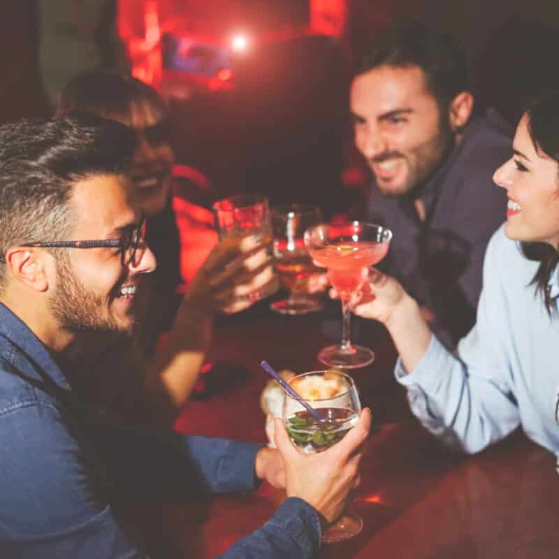 Group of friends raising glasses in a toast at a dimly lit bar or club photo.
