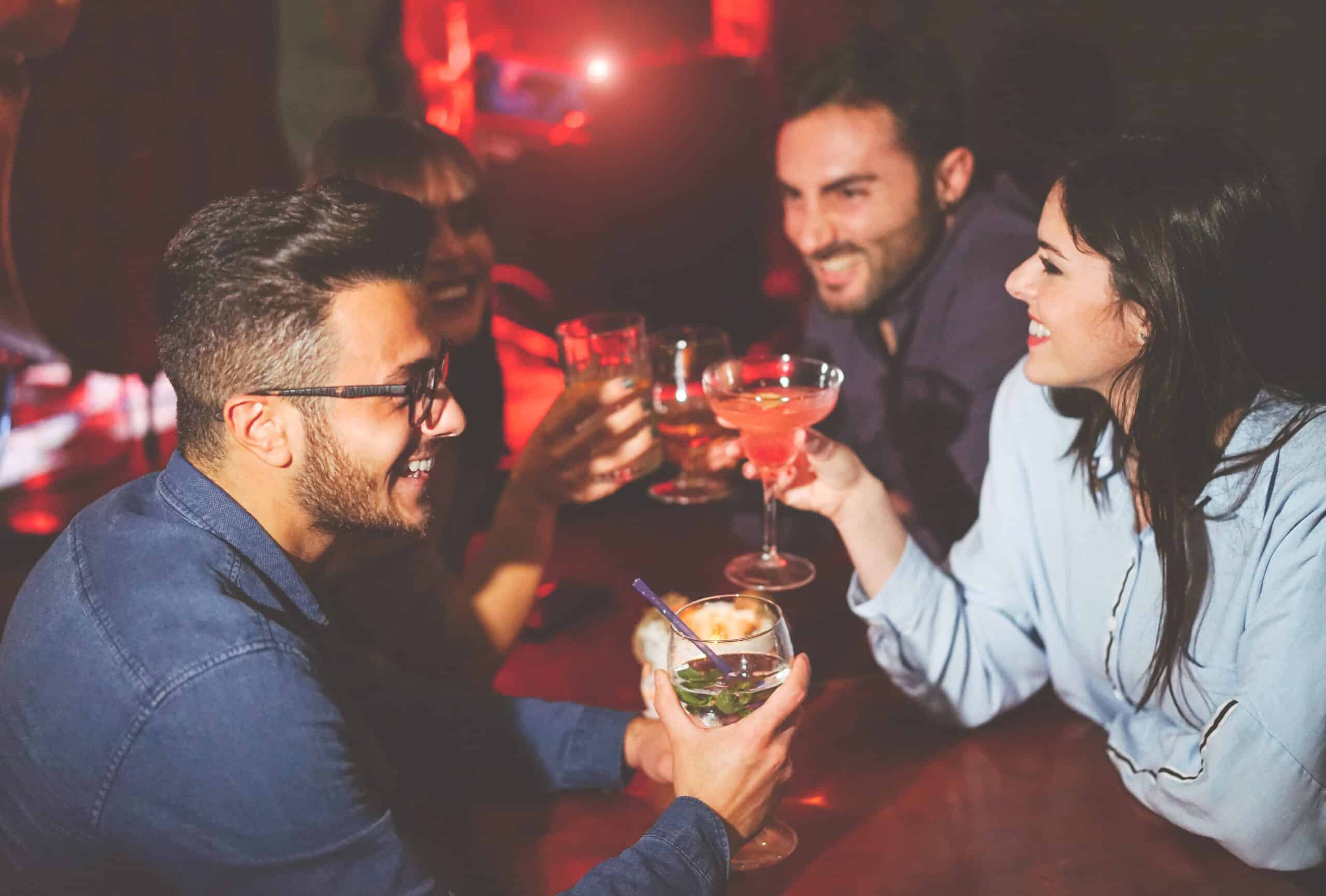 Group of friends raising glasses in a toast at a dimly lit bar or club photo.