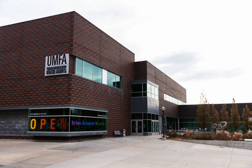 Exterior view of the Utah Museum of Fine Arts building with brick facade and large glass windows, sign reading UMFA.